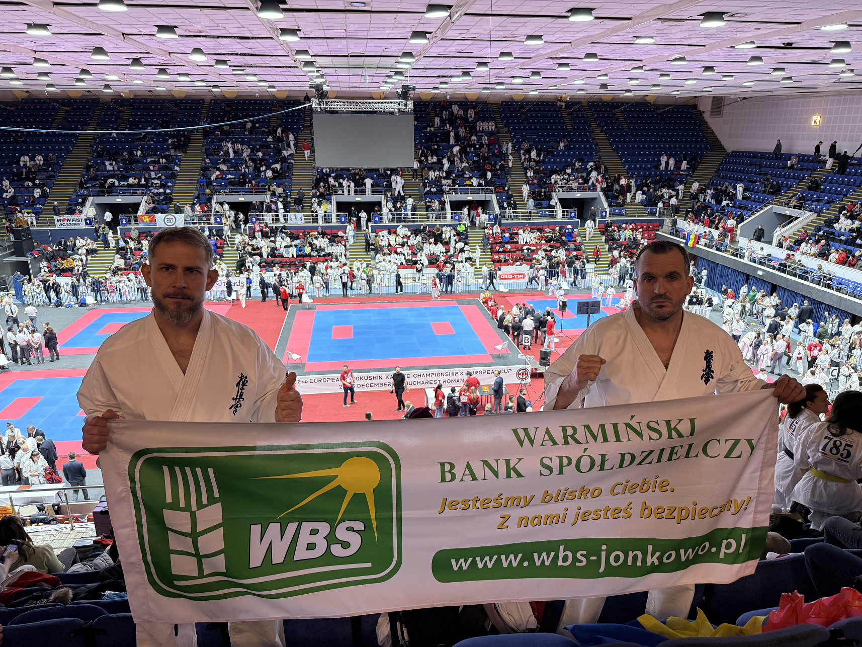 Marek Bębenek i Rafał Rogala na trybunach z banerem Banku