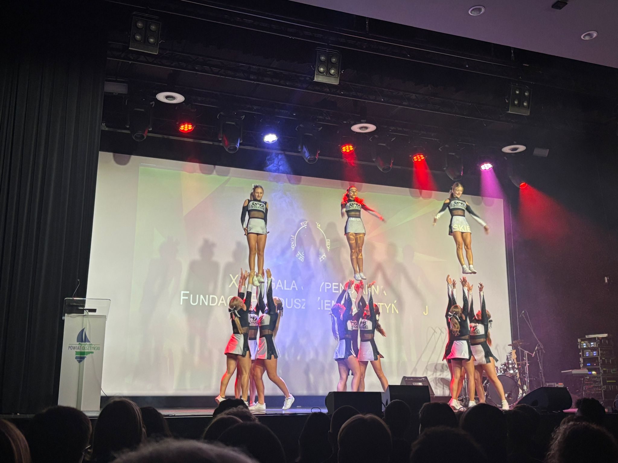 występ artystyczny - dziewczyny w kolumnach trzymające koleżanki 