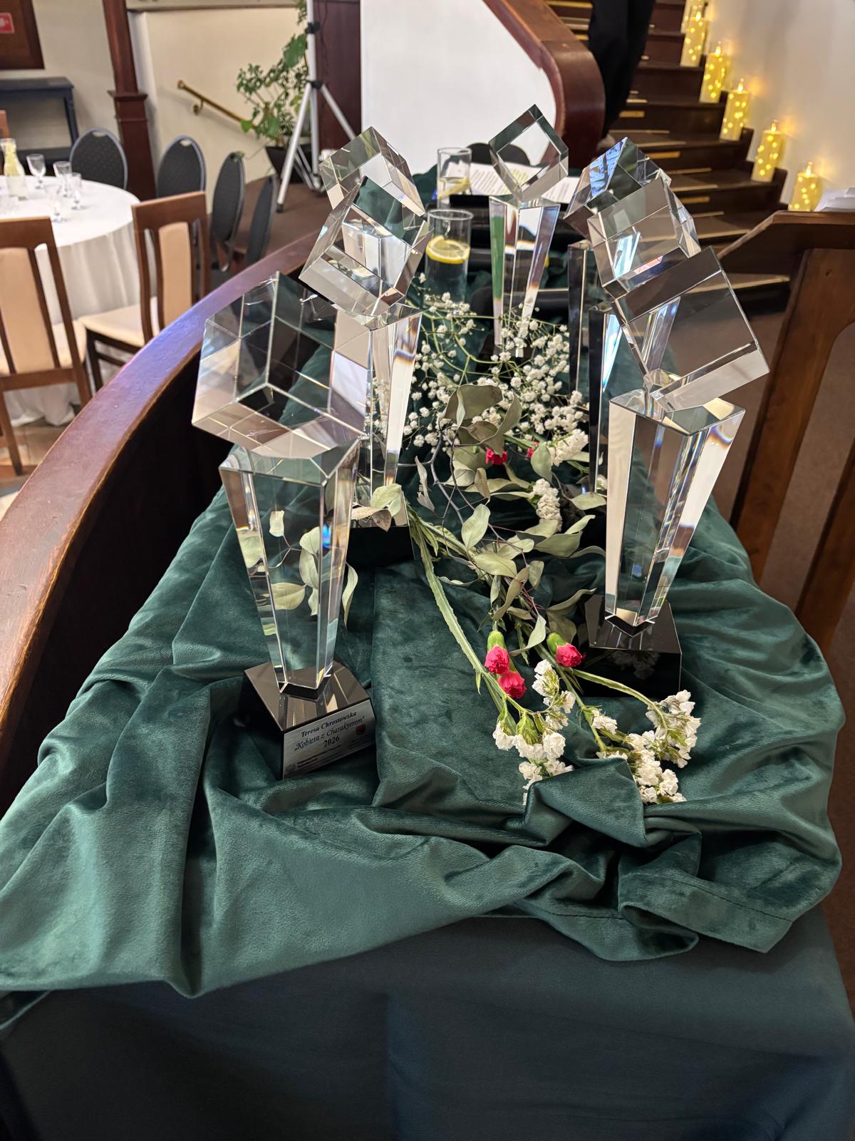 Statuetki na zielonym obrusie z kwiami w środku