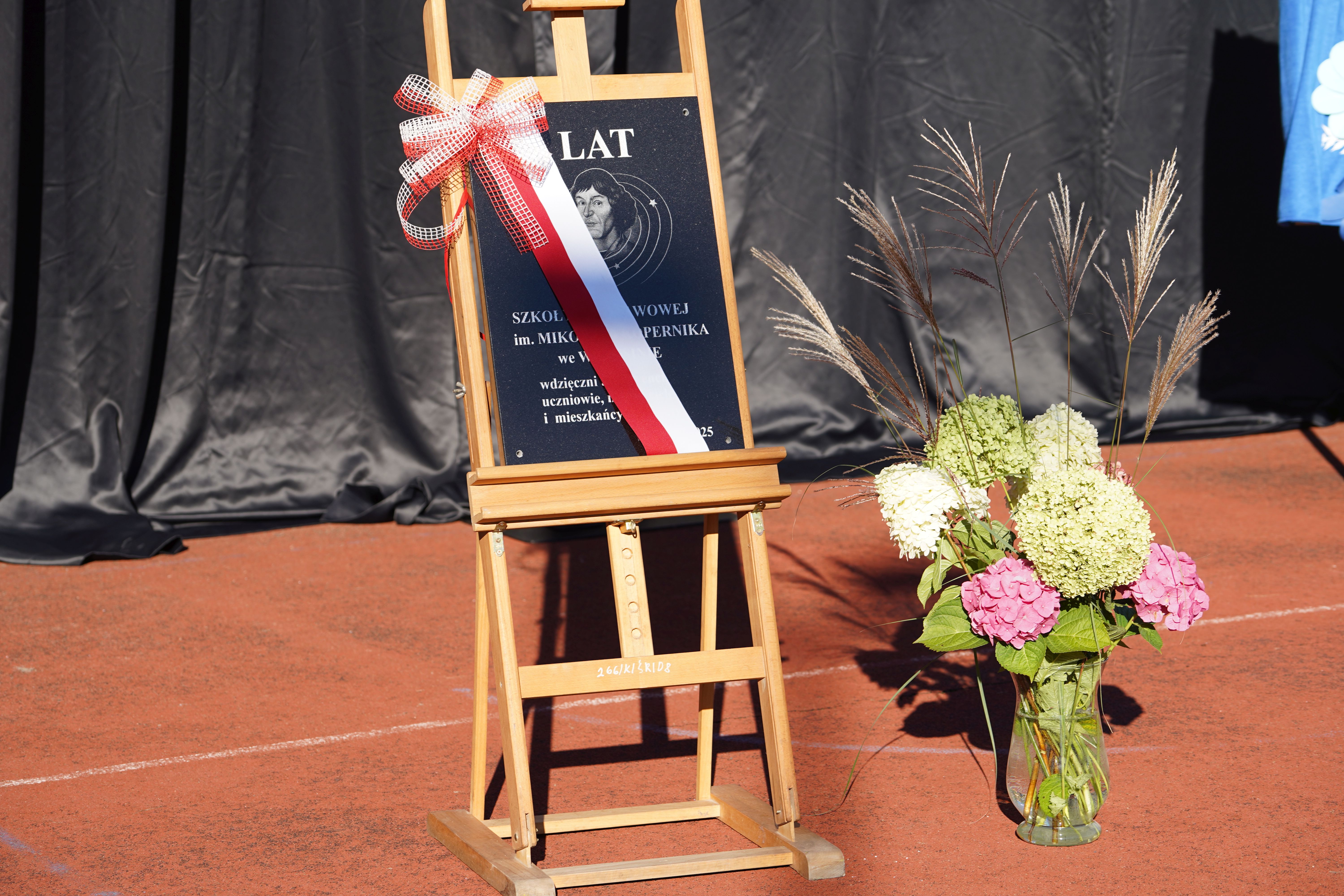 tablica z logo szkoły z szarfą - flagą polski