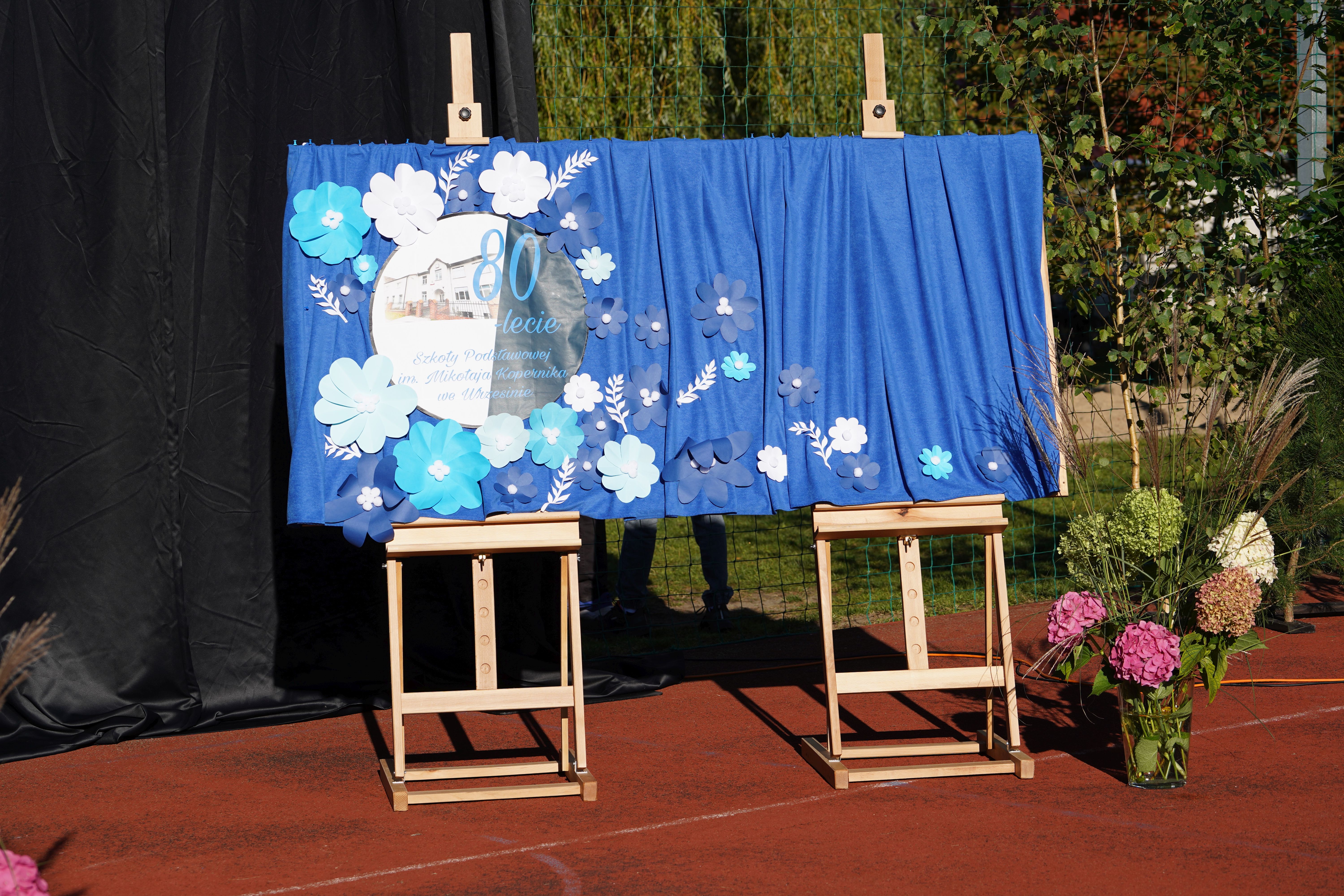 tablica niebieskie tło logo i zdjęcie szkoły napis 80-lat