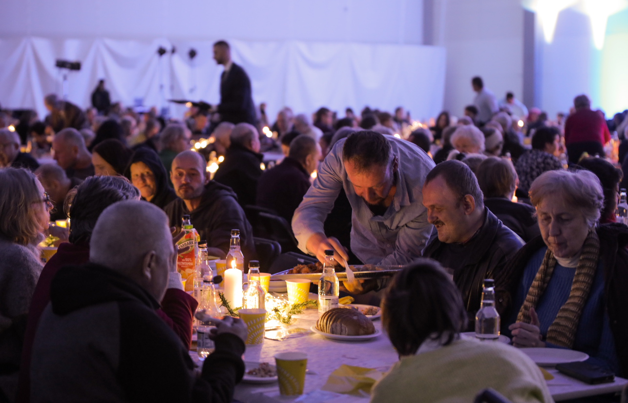 Uczestnicy wigilii przy stole z zapalonymi świeczkami